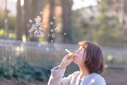 Young woman playing with soap bubbles in the evening