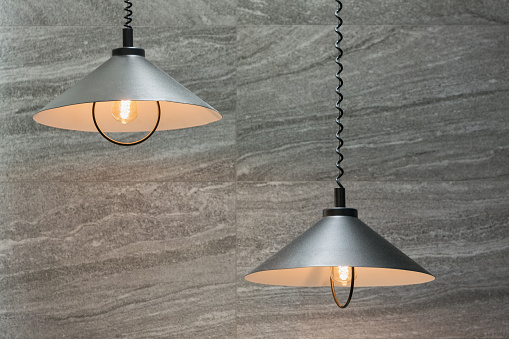 Decorating industrial lamps made off metal in cone shape and against stone wall tiles