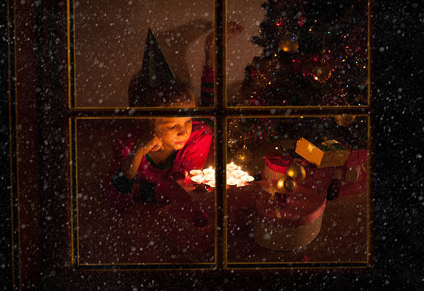 istock cute little boy blowing candles at Christmas viewed from outside 637892746