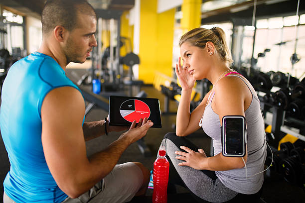istock Young woman discussing workout progress with fitness instructor 637893794