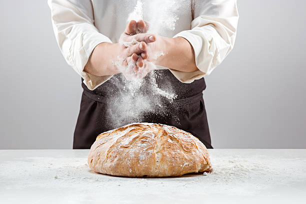 The male hands in flour and rustic organic loaf of The hands of baker man and rustic organic loaf of bread - rural bakery on gray baking bread photos stock pictures, royalty-free photos & images