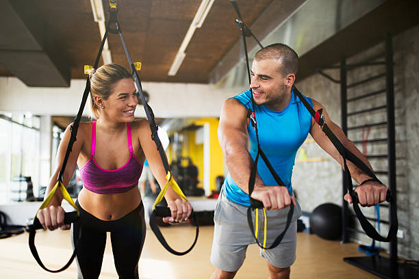 istock Couple doing arm exercises with suspension straps at gym. 637894034