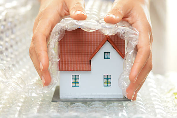 Woman hands covering a model house with bubble wrap stock photo