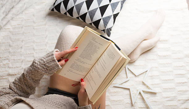 istock Woman relaxing with a book at her home 637899226