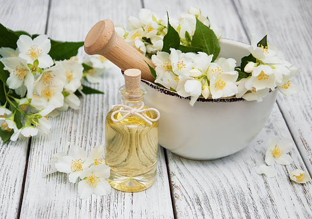 Massage oil with jasmine flowers Massage oil with jasmine flowers on a wooden background winter jasmine stock pictures, royalty-free photos & images