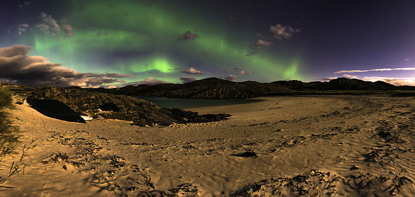 The Aurora Borealis, also known as the Northern lights, lights uo the clear starry sky above Achmelvich beach, Sutherland, in the Highlands of Scotland, UK.