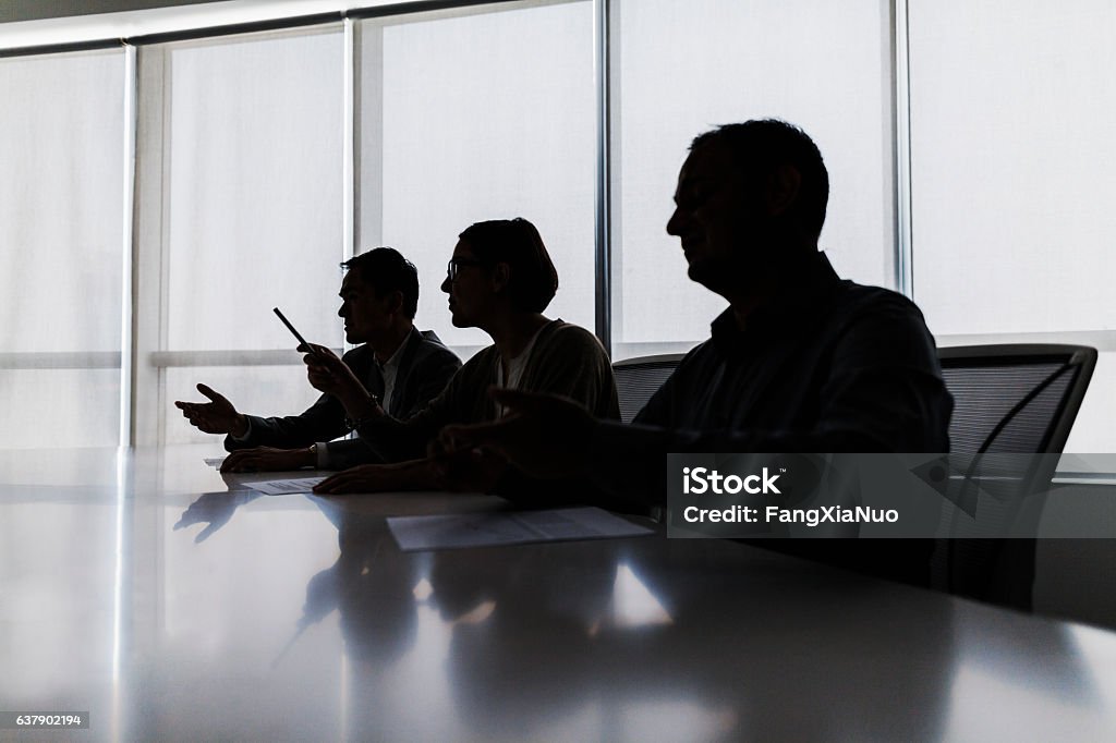 Silhouette of business people negotiating at meeting table Governing Board Stock Photo
