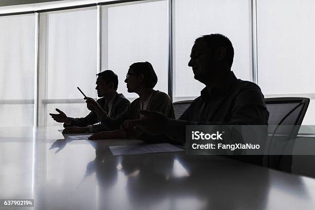 Silhouette Of Business People Negotiating At Meeting Table Stock Photo - Download Image Now