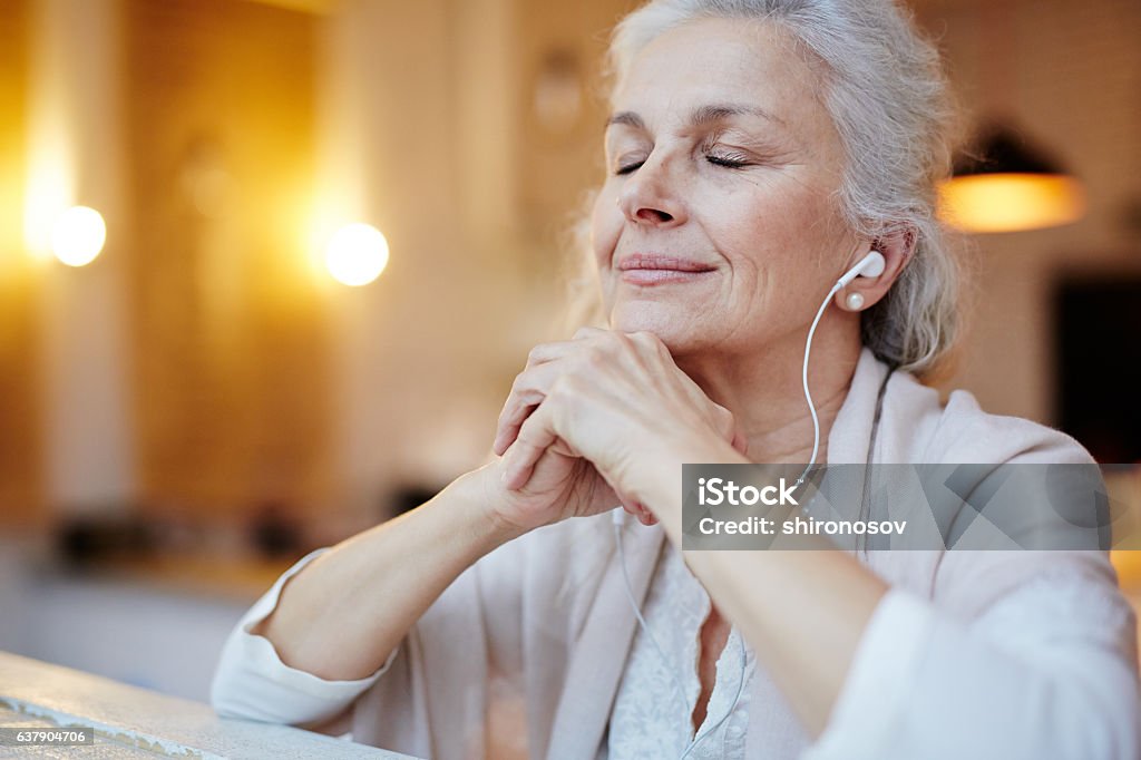 Music for relax Mature woman with earphones listening to music Music Stock Photo