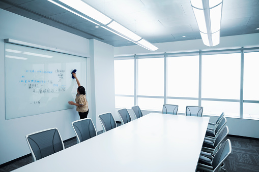 Custodial staff wiping white board clean in meeting room