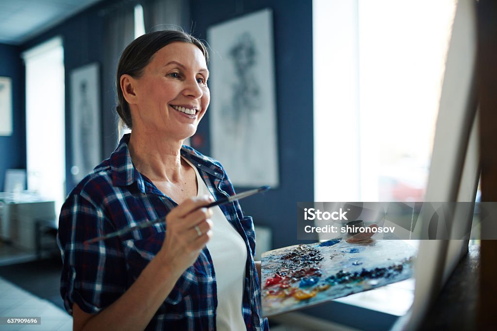 Successful painter Happy elderly woman looking at her painting in art studio Painting - Activity Stock Photo