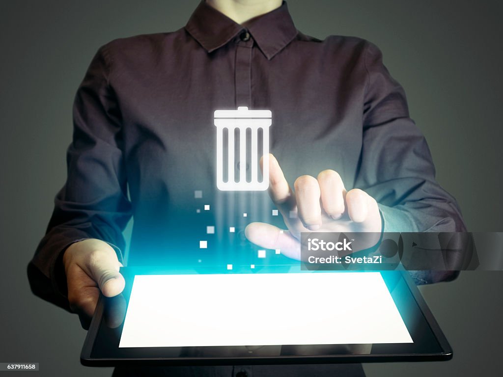 trash can Image of a girl with tablet in her hands. She presses trash can icon. The concept of deleting files, contacts, putting in order, cleaning service etc Computer Stock Photo
