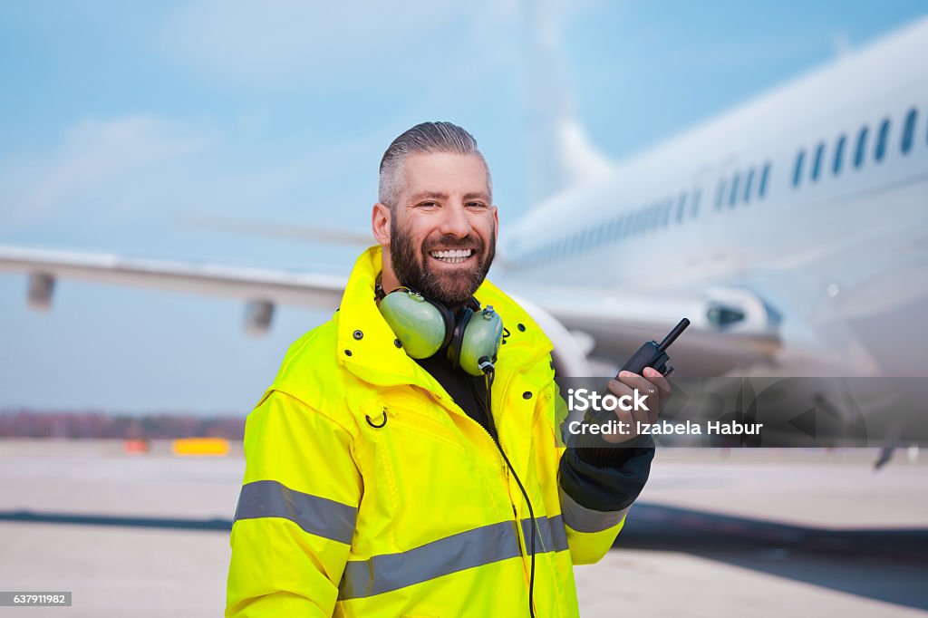 Ground crew using walkie-talkie outdoor in front of aircraft Ground crew using walkie-talkie outdoor in front of aircraft at the airport, smiling at camera. Airport Stock Photo
