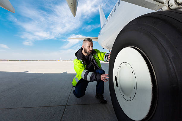 pracownik lotniska sprawdza opony - airplane airport air vehicle ground crew zdjęcia i obrazy z banku zdjęć