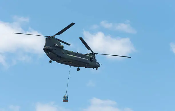 Double rotor, heavy airlift, military helicopter, in flight, carrying cargo.