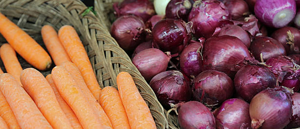 basket of orange carrots and red onions for sale at the greengrocer