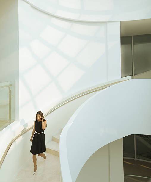 mujer en la escalera descendente del teléfono en el edificio moderno - architecture details fotografías e imágenes de stock