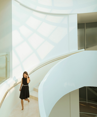 Woman on phone descending staircase in modern building