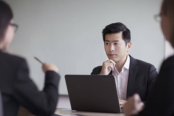 businessman looking across table in office meeting - chinese ethnicity student china asian ethnicity imagens e fotografias de stock