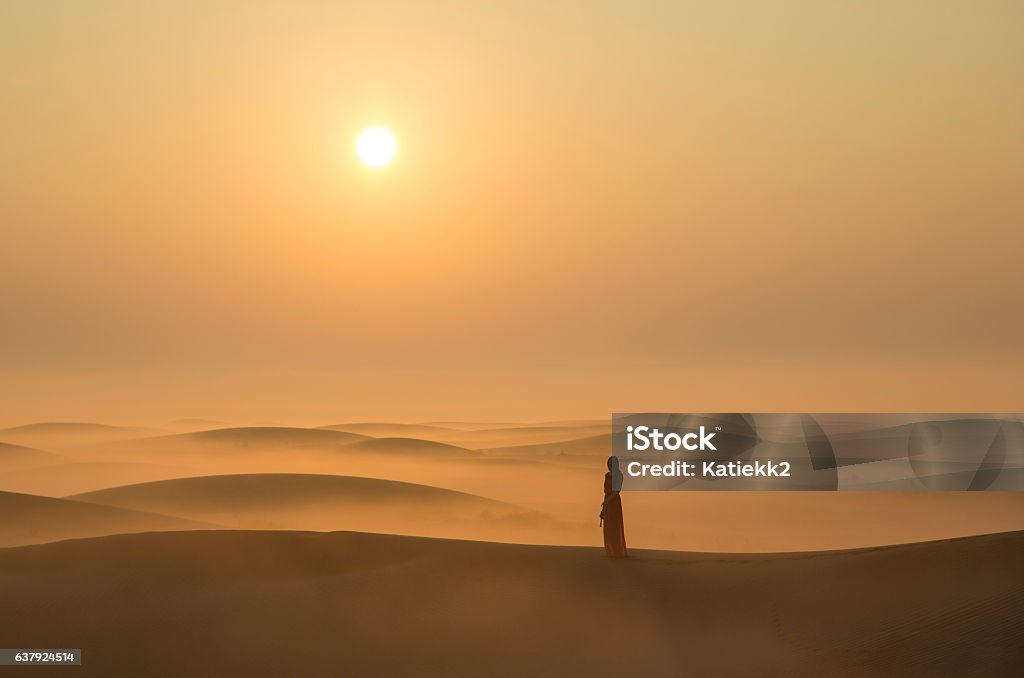 a woman in a desert at sunrise near Dubai A woman in a mist in desert landscape at Sunraise near Dubai, UAE Desert Area Stock Photo
