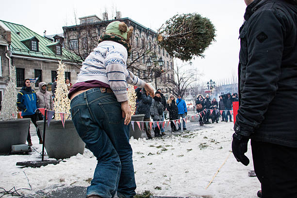 Man throwing a christmas tree in a competition Montreal, Canada - January 30, 2016: People participate at a Christmas Tree Toss Competition at Place Jacques-Cartier, in Old Montreal. The festive activity attracted dozens of Montrealers and tourists. place jacques cartier stock pictures, royalty-free photos & images