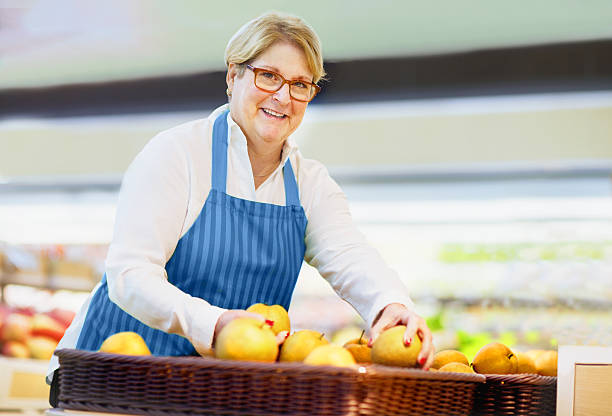 Woman arranging pears at grocery store Woman arranging pears at grocery store perfect pear stock pictures, royalty-free photos & images