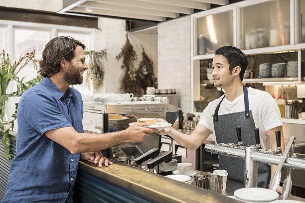Young man serving male customer at bar in restaurant
