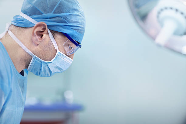 доктор смотрит вниз на пациента в операционной больницы - surgical scrub стоковые фото и изображения