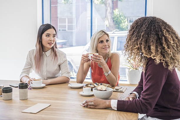 istock Three young women sitting in meeting with coffee and snacks 637926328