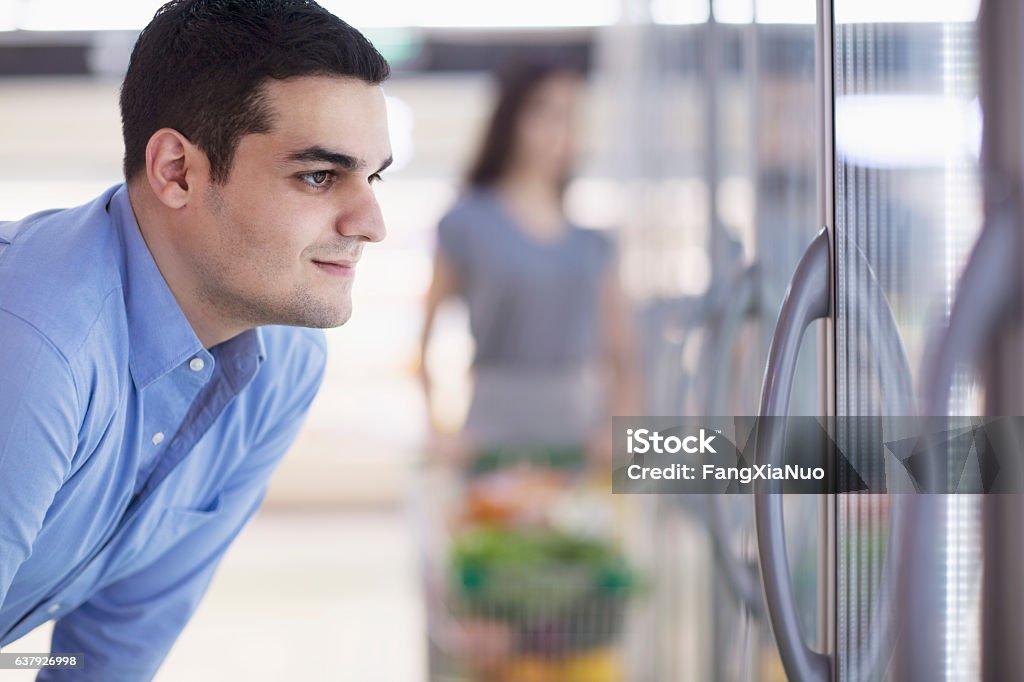 Shopper looking into freezer at supermarket Frozen Stock Photo