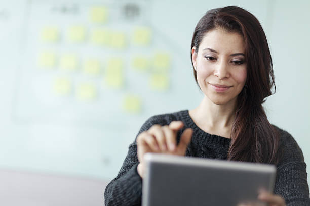 femme travaillant sur tablette informatique dans un studio de bureau - learning business technology leadership photos et images de collection