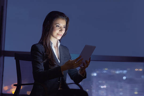 istock Businesswoman viewing tablet computer in office at night 637929324