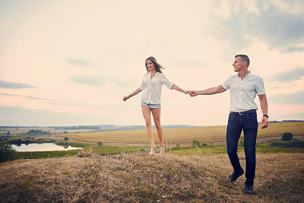 istock Happy couple holding hands and walking together outdoors at sunset 637933892