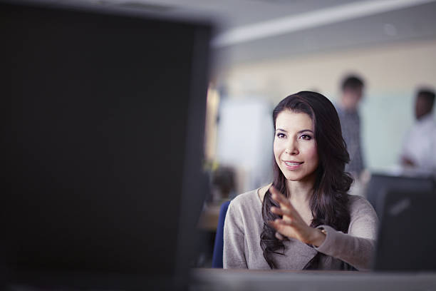 mujer hablando con su colega frente a la computadora - connect the dots audio fotografías e imágenes de stock