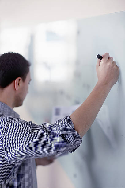 istock Man writing notes from diagram onto whiteboard in office 637934334