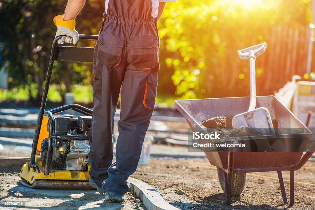 Brick Path Construction Brick Path Construction. Caucasian Construction Worker with Plate Compactor. Brick Paving Theme. Yard - Grounds Stock Photo