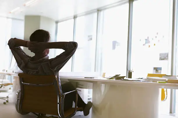 Man sitting arms behind head relaxed in office meeting room