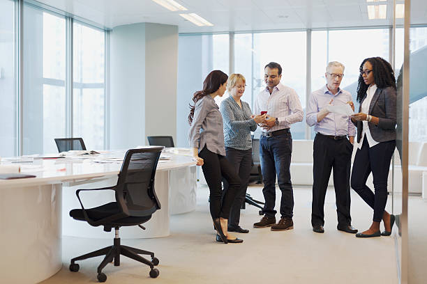 istock Group of business colleagues standing together talking in open office 637943672