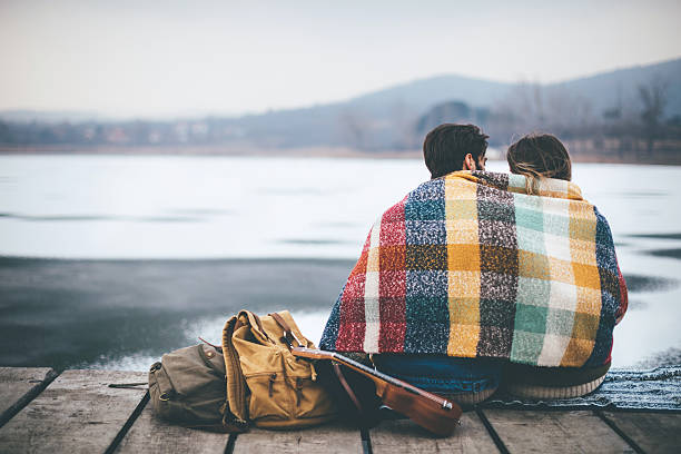 romántica pareja joven abrazada junto al lago en invierno - travel adventure winter cold fotografías e imágenes de stock