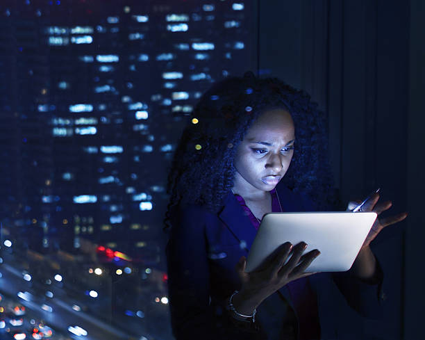 mujer trabajando en tablet por la noche en la oficina - final touch fotografías e imágenes de stock