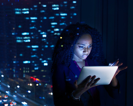 Woman working on tablet computer at night in office