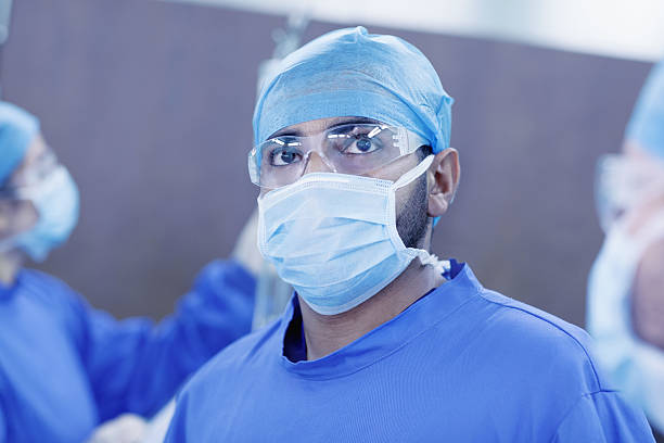 доктор смотрит вверх, чтобы контролировать в операционной больницы - hair net nurse scrubs asian ethnicity стоковые фото и изображения
