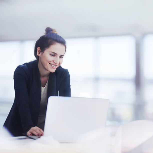 明るいオフィスでラップトップに取り組んでいる女性 - cheerful business person strategy people ストックフォトと画像