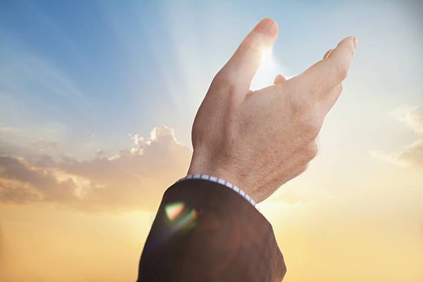 istock Man raising hand gesture praise to sunset dawn in sky 637950198