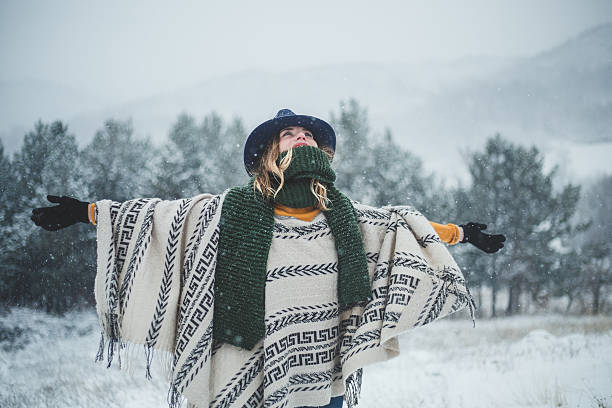 bella donna che alza le mani, godendosi nella fredda giornata invernale innevata - poncho foto e immagini stock