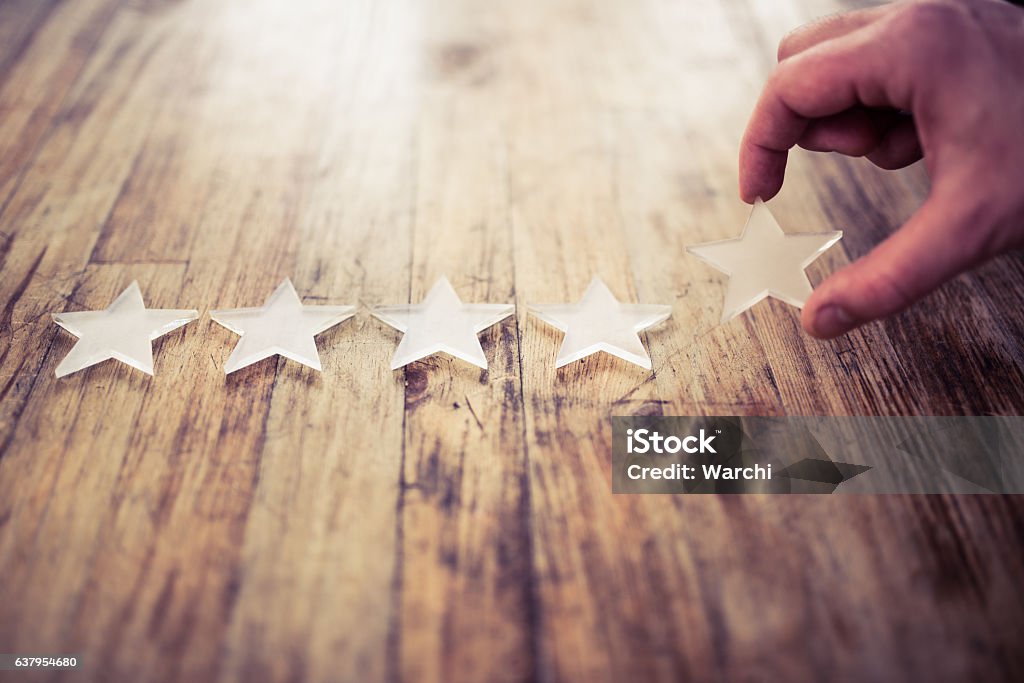 The best rating Hand arranging 5 stars on a wooden desk Organization Stock Photo