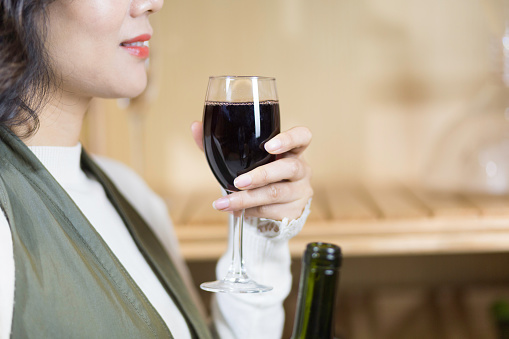 young asian woman holds red wine