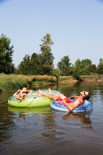 A couple take float in tubes down the river during the summer.A couple take float in tubes down the river during the summer.