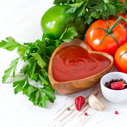 Tomato ketchup sauce in a wooden bowl and ingredients.