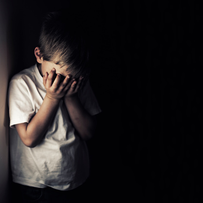 Niño llorando deprimido sosteniendo la cabeza en las manos photo